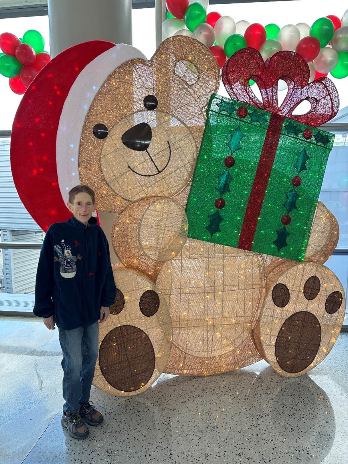 A person standing next to a large teddy bear

Description automatically generated
