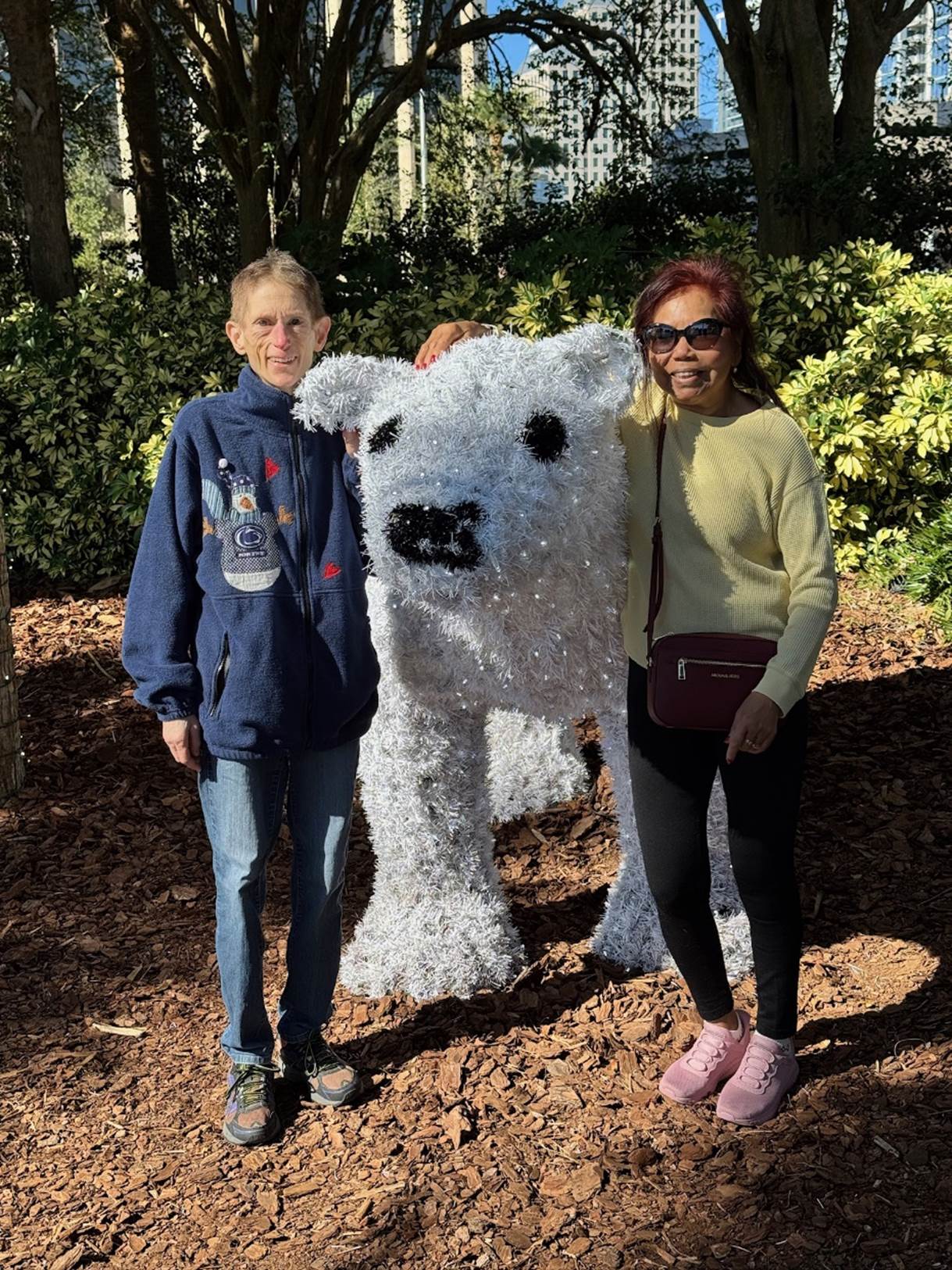 Two people standing next to a statue of a polar bear

Description automatically generated