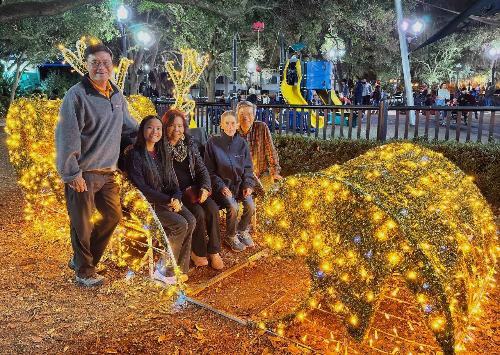 A group of people sitting on a bench with lights

Description automatically generated