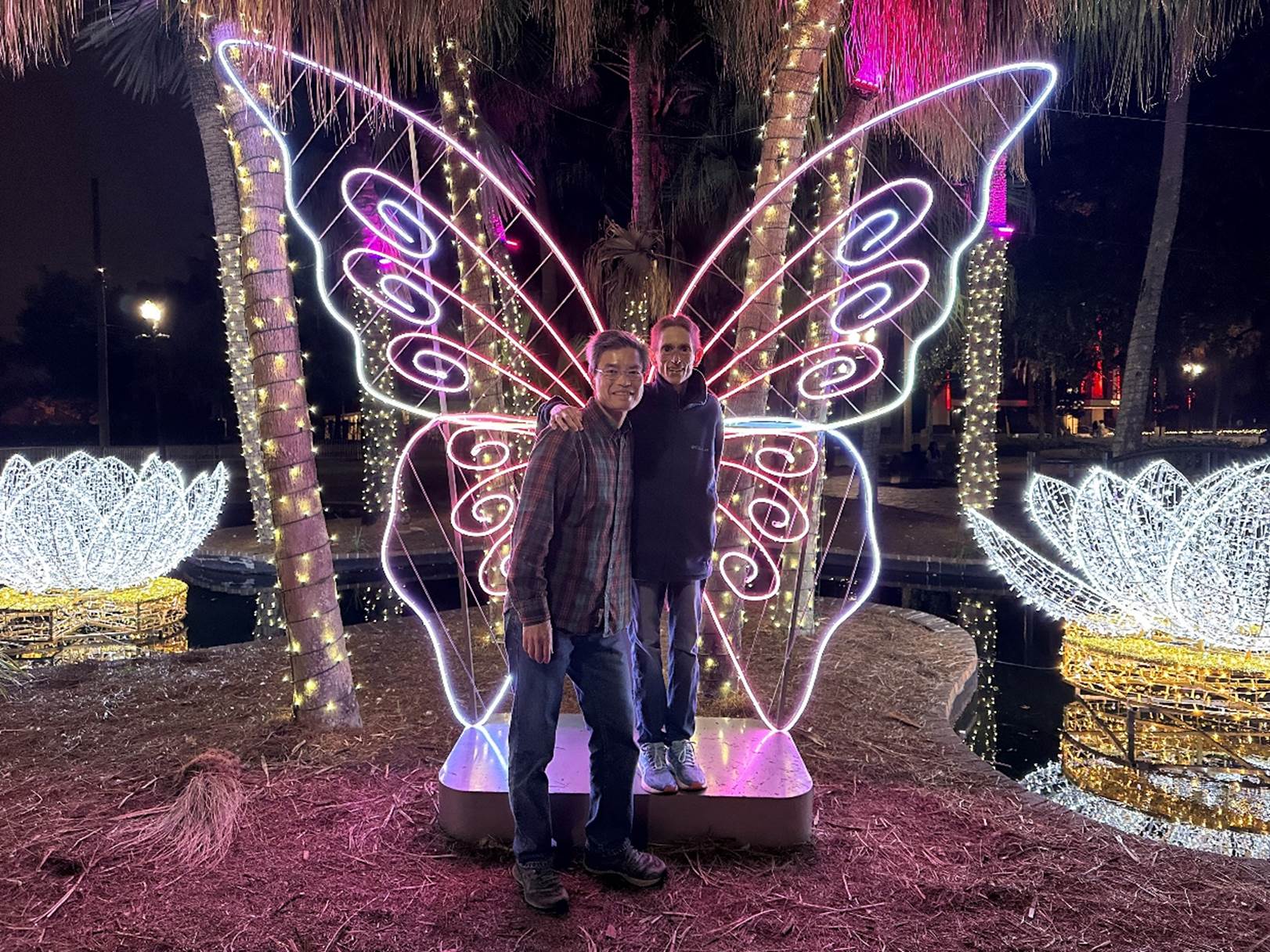 Two men standing in front of a lighted tree

Description automatically generated
