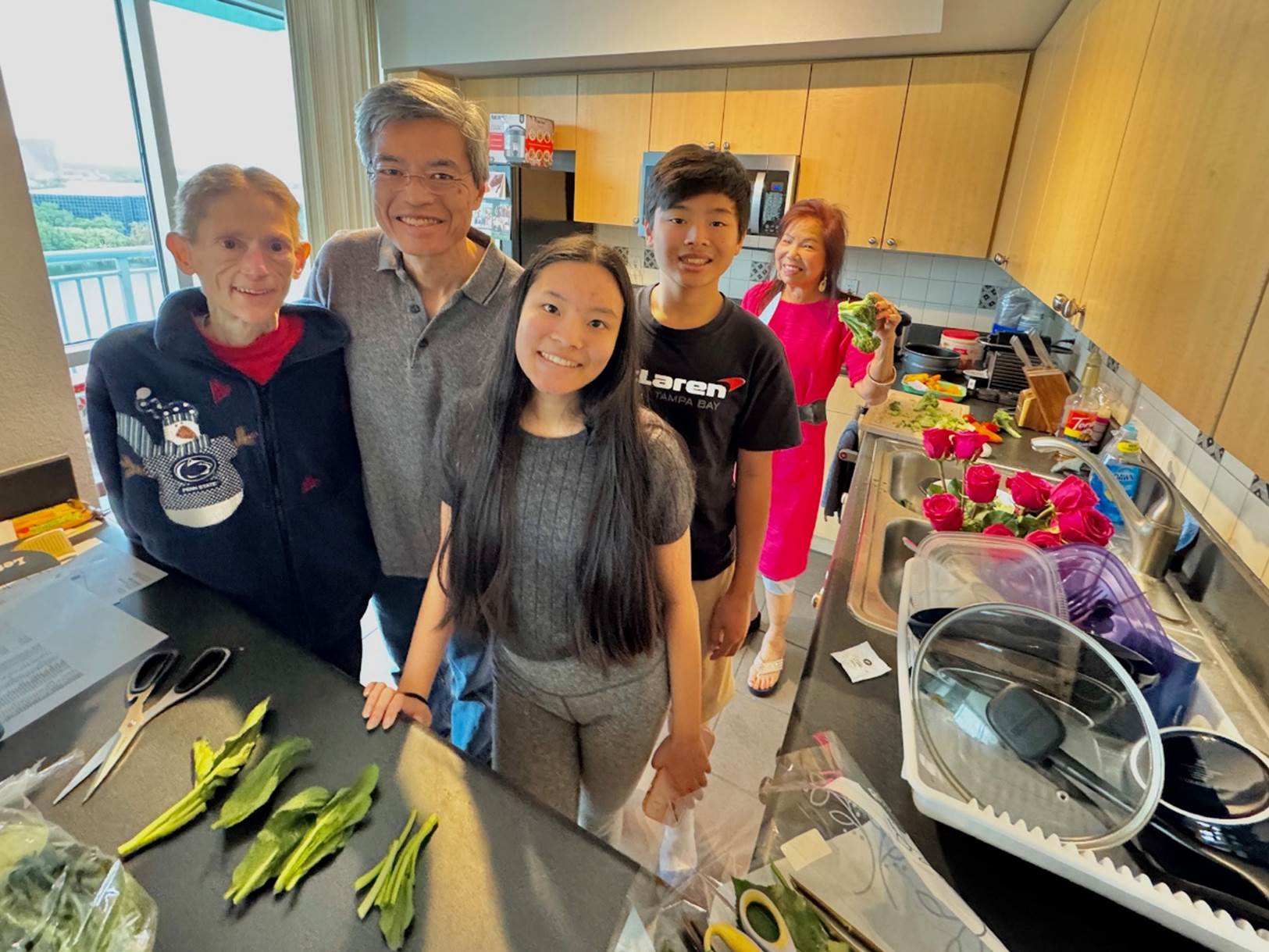 A group of people standing in a kitchen

Description automatically generated