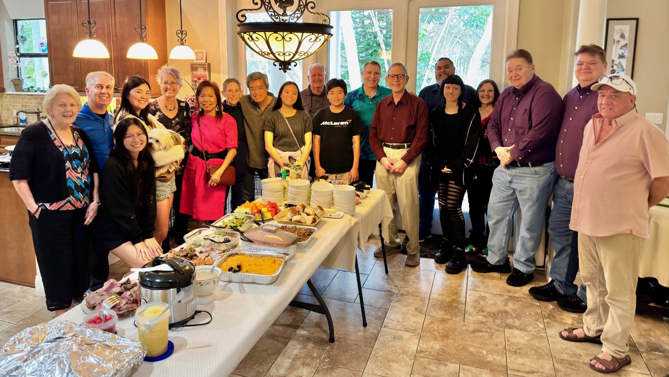 A group of people standing around a table with food

Description automatically generated