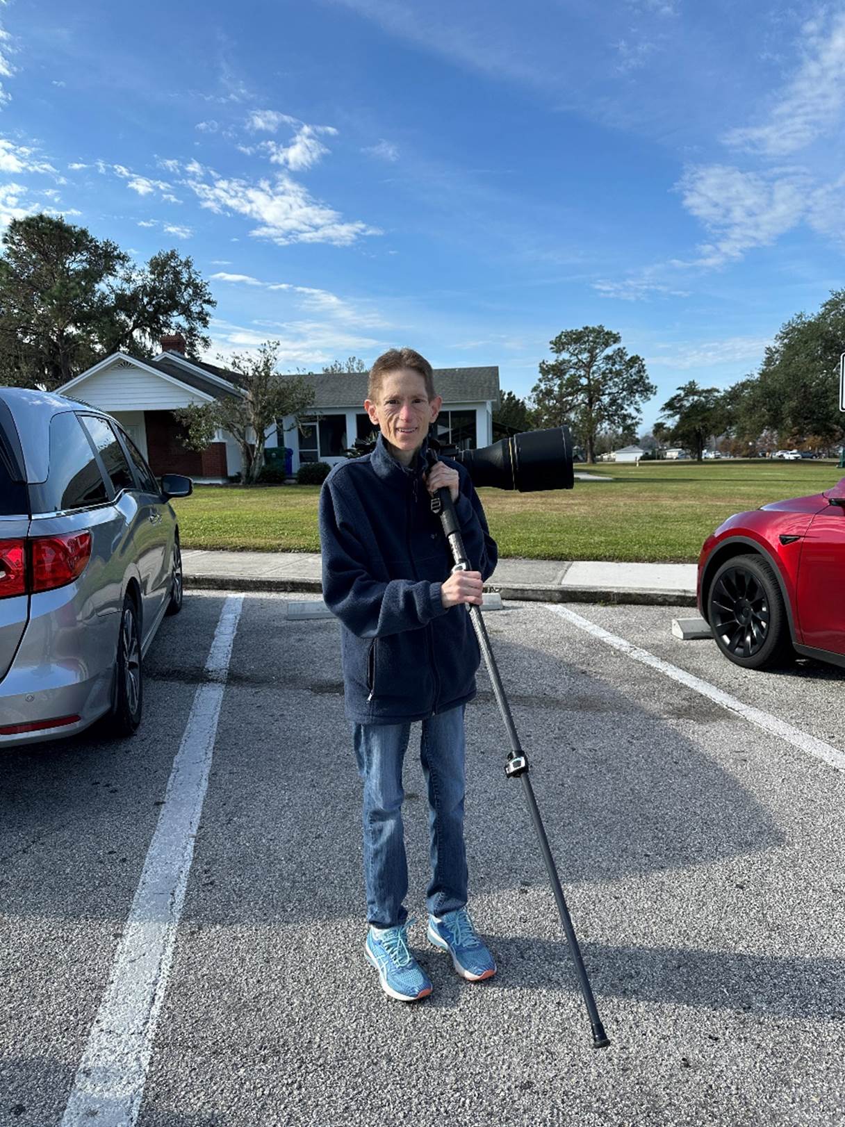 A person standing in a parking lot holding a pole

Description automatically generated