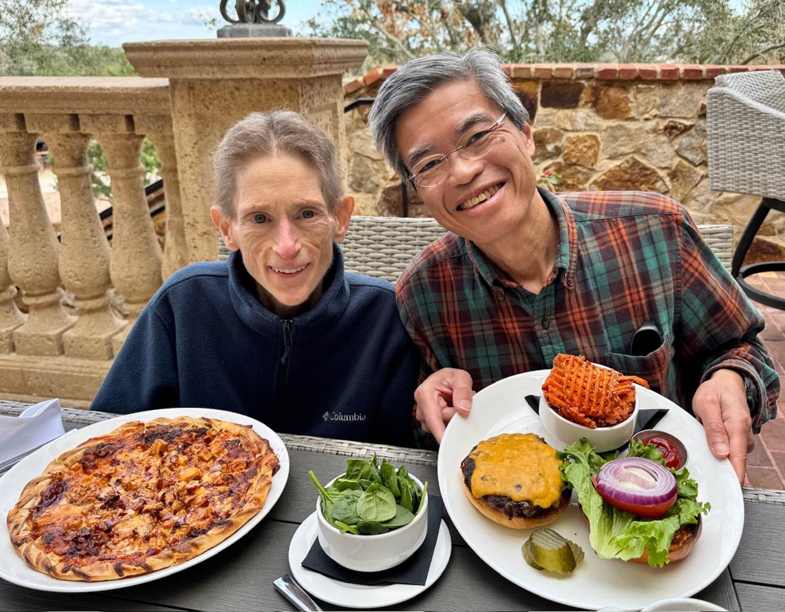 A person and person sitting at a table with plates of food

Description automatically generated