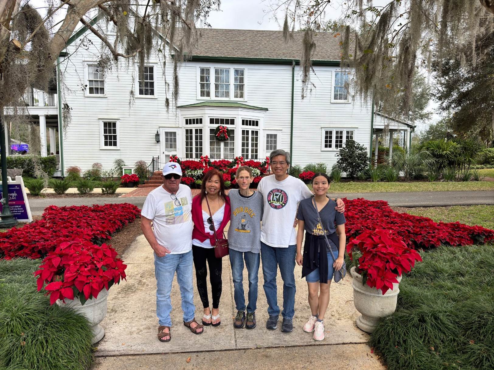 A group of people posing for a photo in front of a house

Description automatically generated