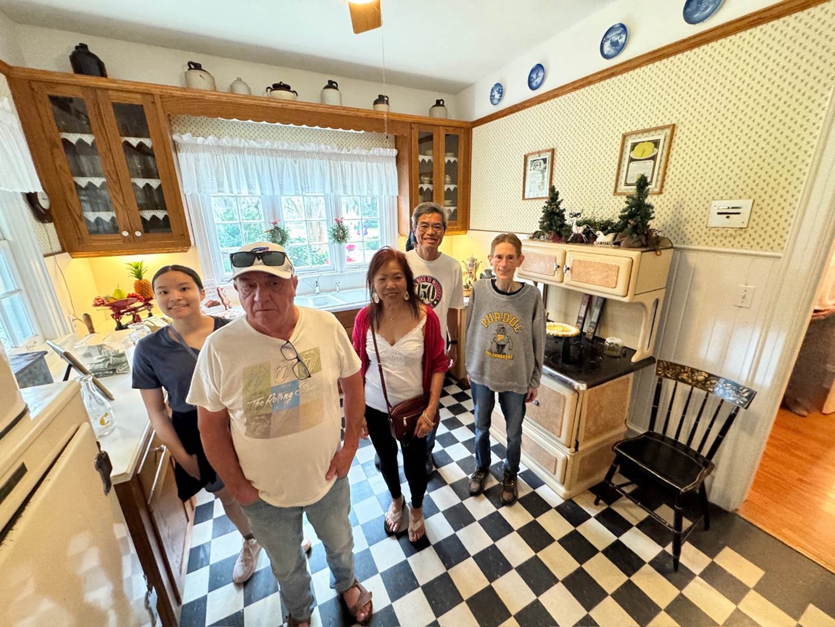 A group of people standing in a kitchen

Description automatically generated