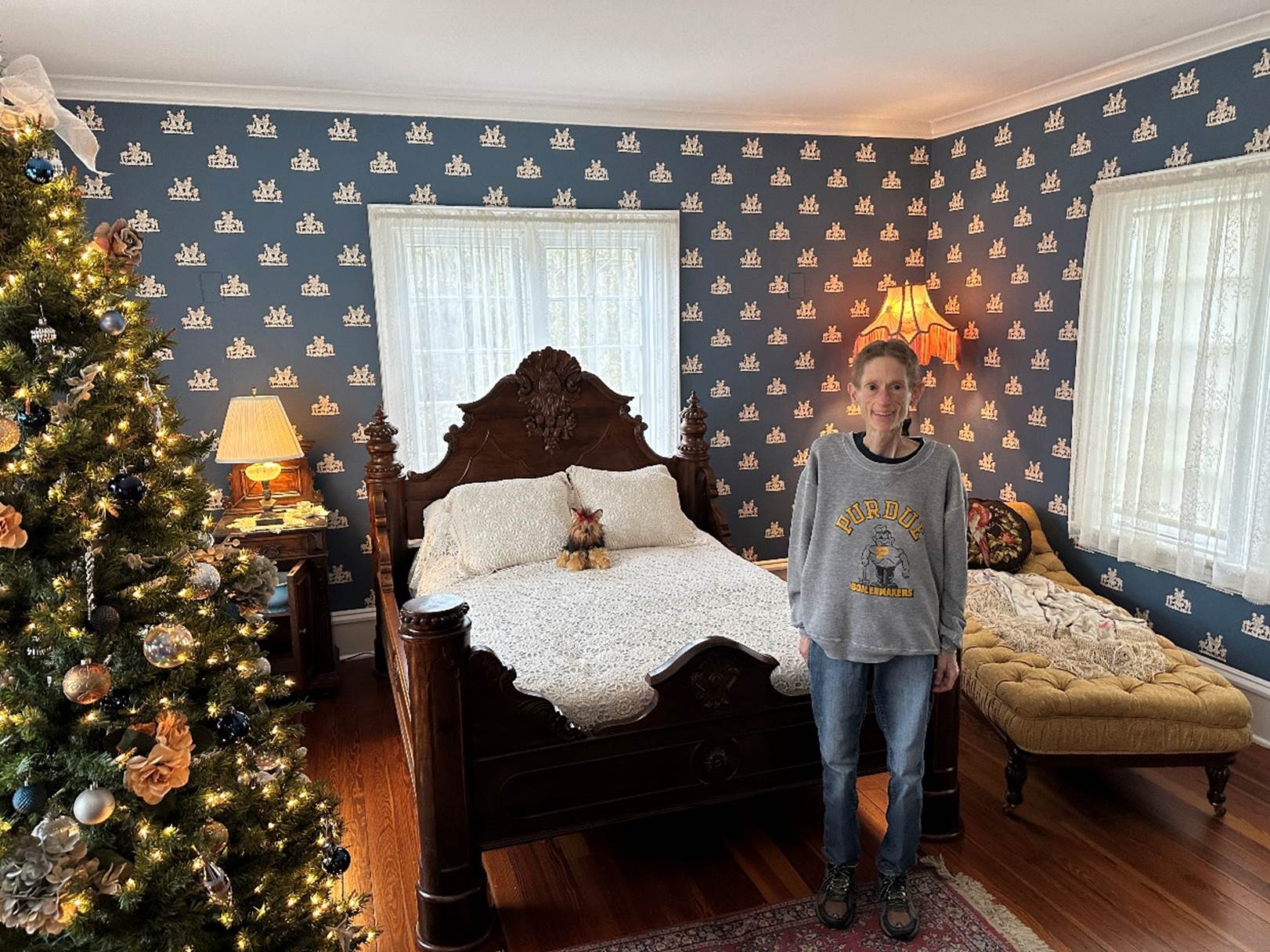 A person standing in a room with a christmas tree

Description automatically generated