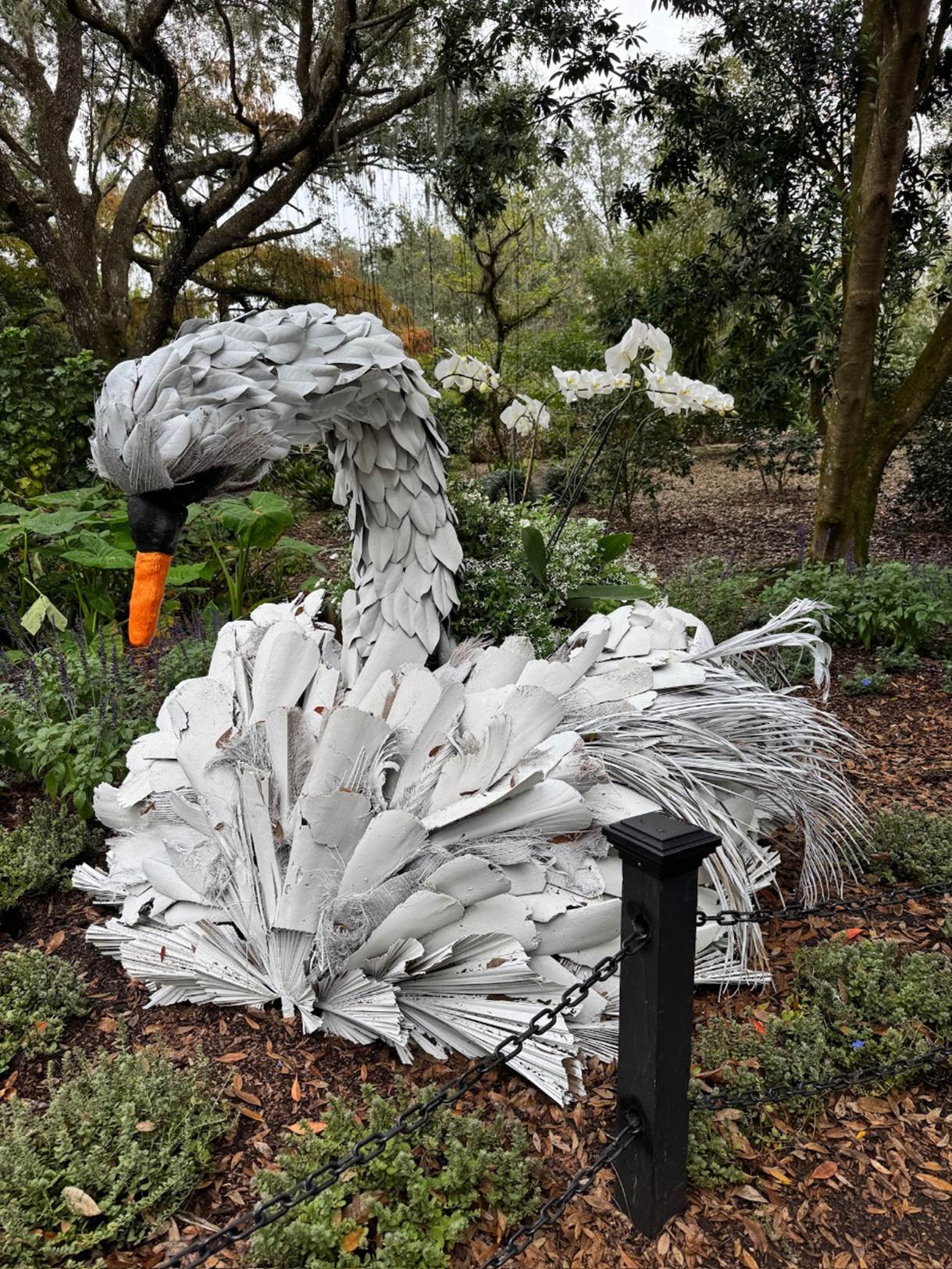 A white swan statue in a garden

Description automatically generated
