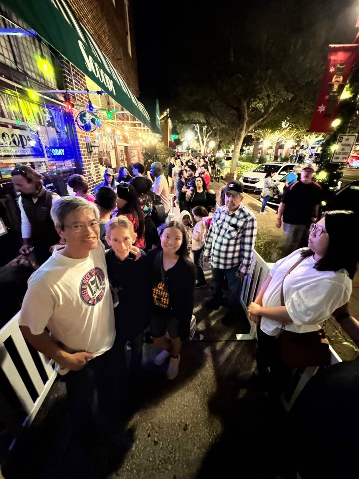 A group of people standing on a sidewalk

Description automatically generated