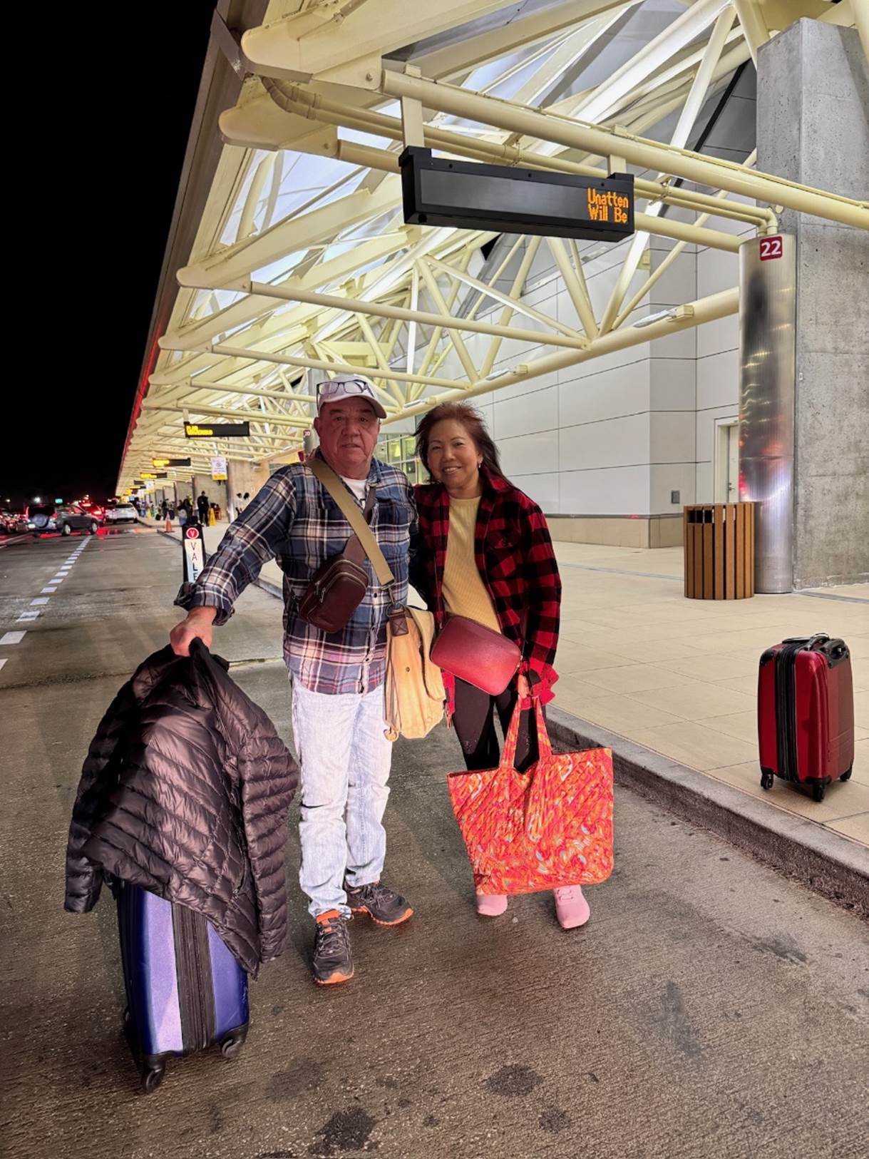 A person and person standing on a sidewalk with luggage

Description automatically generated