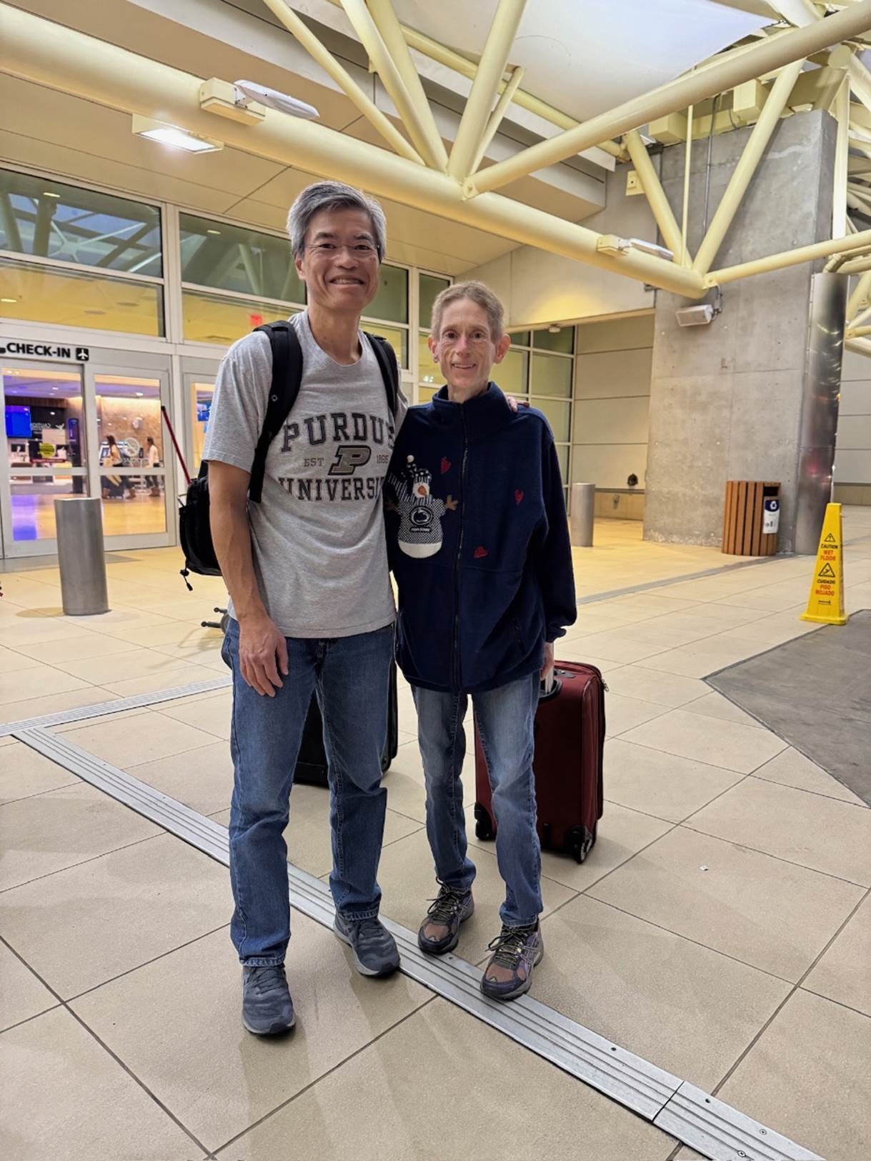 A person and person standing in a building with luggage

Description automatically generated